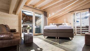 Une chambre confortable avec un grand lit, un plafond en bois et une porte-fenêtre coulissante donnant sur un balcon.