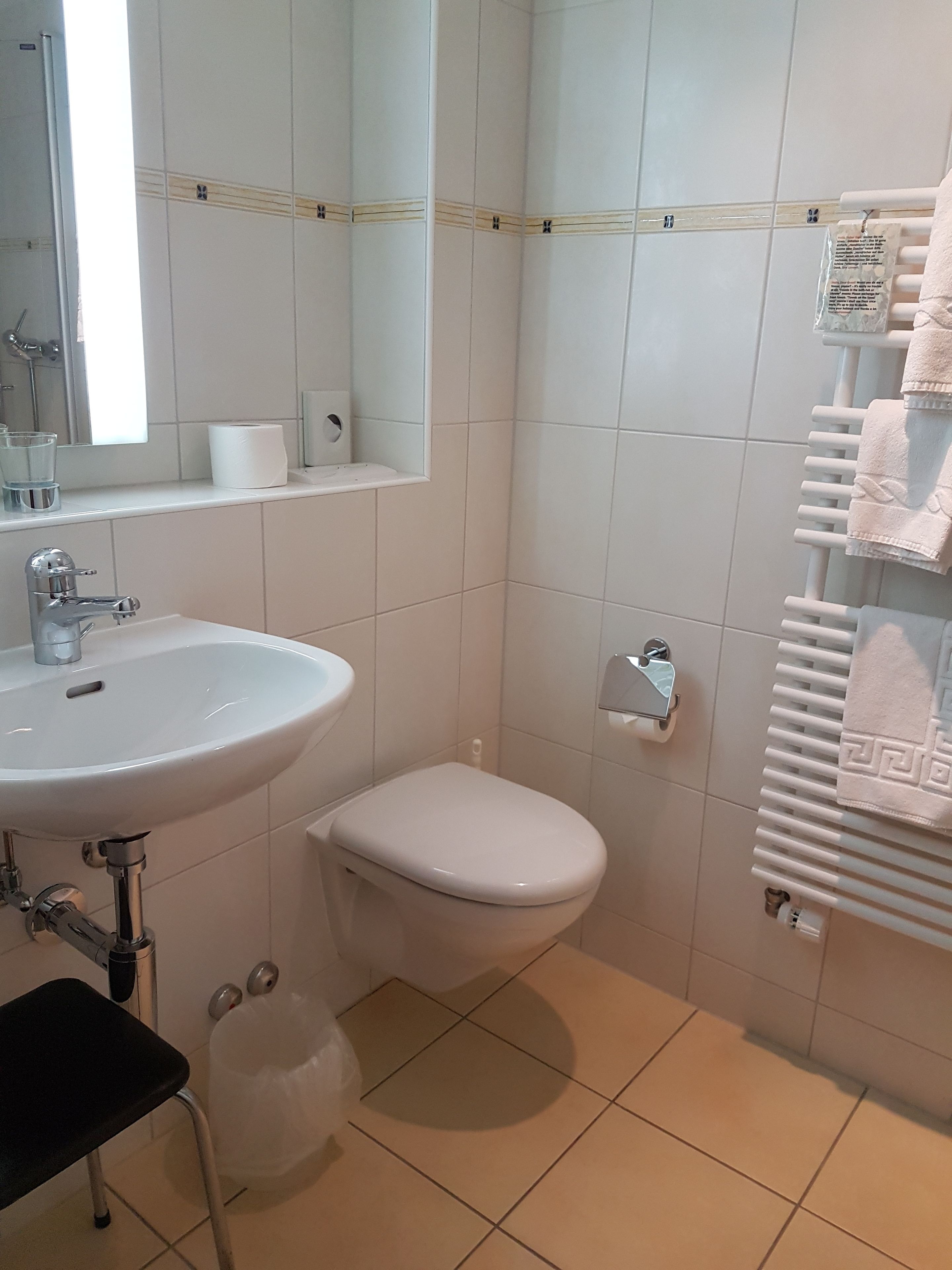 Une salle de bain avec un lavabo blanc, des toilettes et un porte-serviettes.