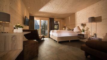 A modern bedroom with a wooden ceiling, a large bed, a sofa, and a desk with a lamp.