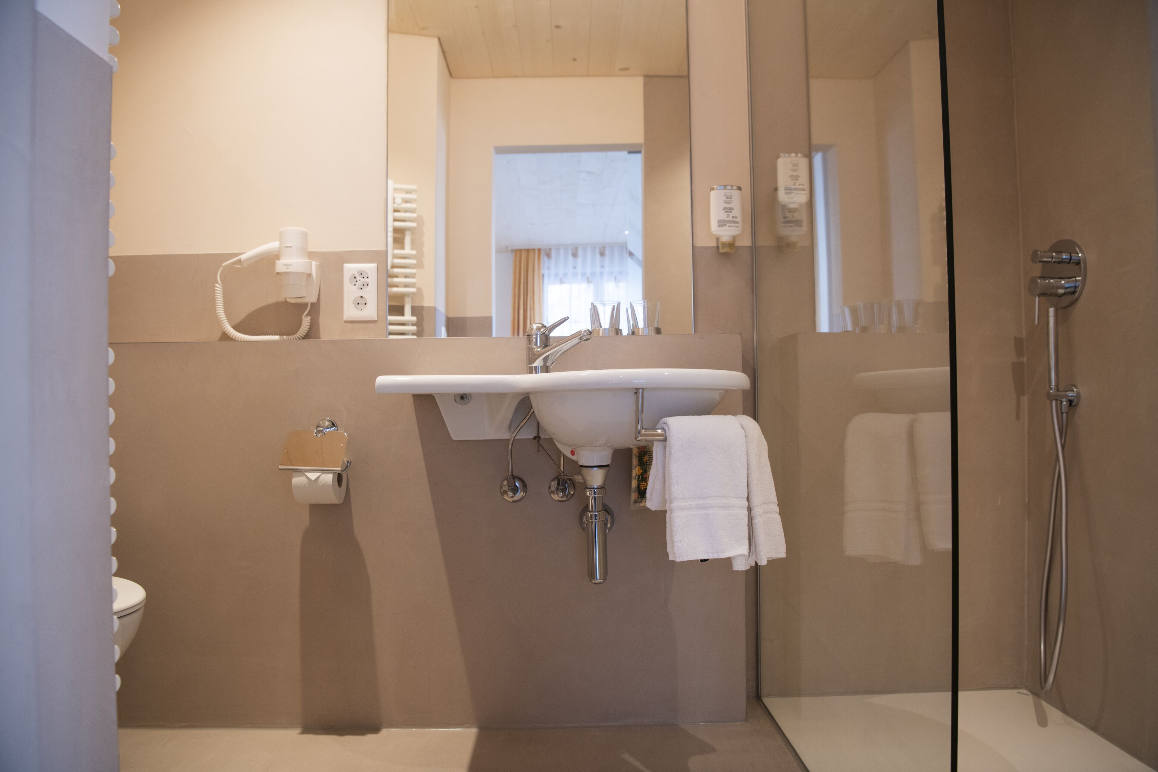 A modern bathroom with a glass shower enclosure, a sink with a mirror, and a toilet.