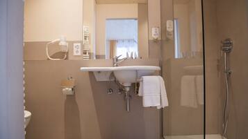 A modern bathroom with a glass shower enclosure, a sink with a mirror, and a toilet.