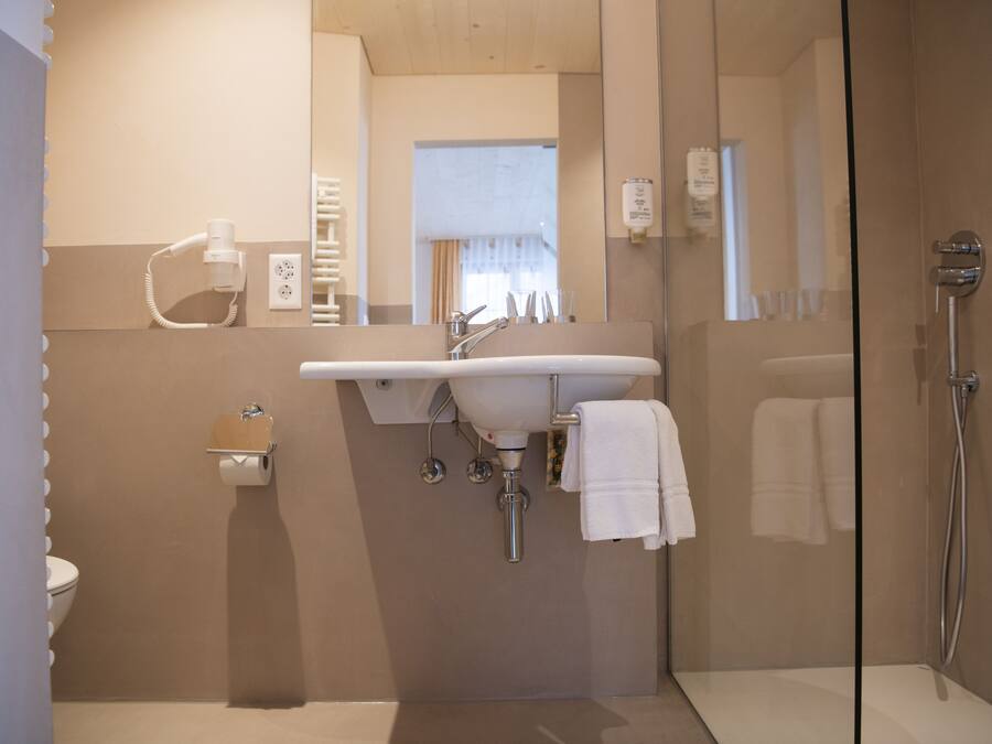 A modern bathroom with a glass shower enclosure, a sink with a mirror, and a toilet.