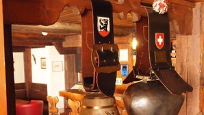 A wooden interior with a bell and a shielded object hanging from the ceiling. - Simmental (Boltigen)
