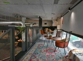 A modern interior with a dining area, a sofa, and a view of the street.