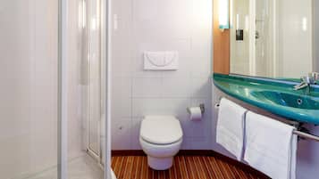 A bathroom with a glass sink, white toilet, and a shower enclosure.