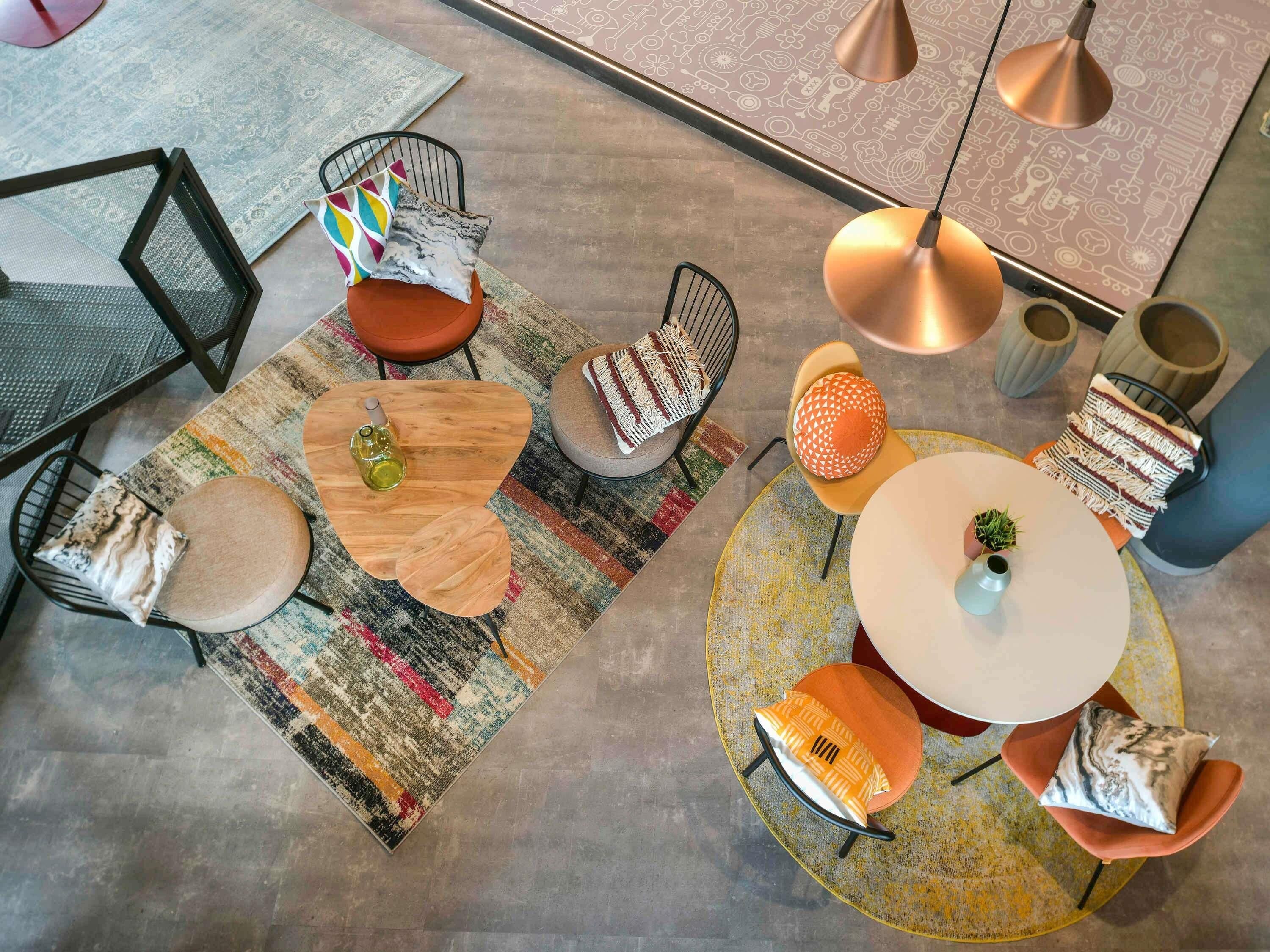 A modern interior with a round table, chairs, a sofa, and a patterned rug.