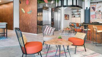 Un interior moderno con una zona de bar, asientos y una cocina visible a través de un mamparo de vidrio.
