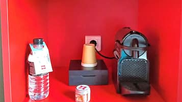 Una habitación roja con una botella de agua, un pequeño recipiente y un altavoz portátil.