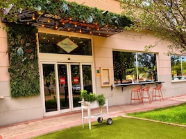 En restaurant med et skilt, der viser 'GrapeBar TAPAS & PASTA', og en grøn væg med planter.