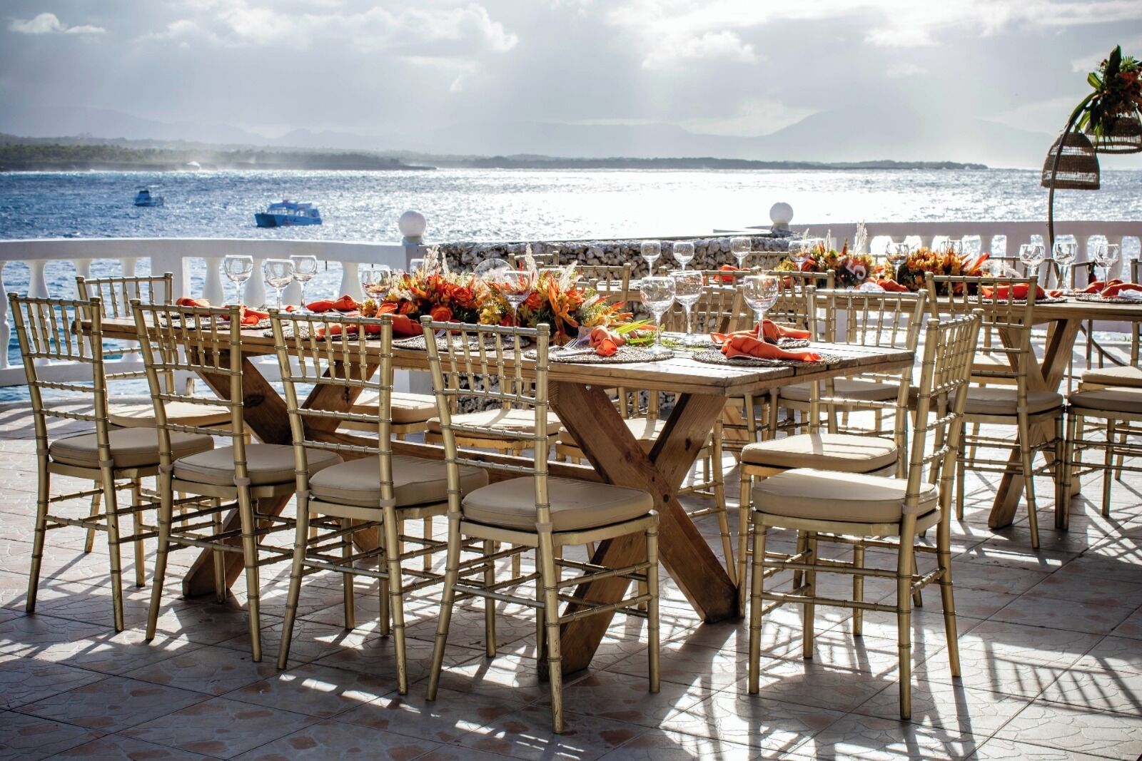 An outdoor dining area with bamboo chairs and tables, set against a scenic ocean view.