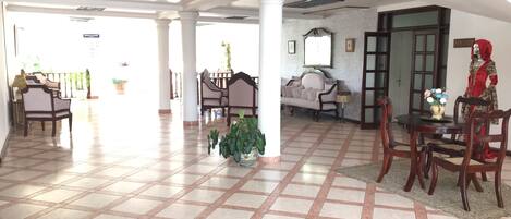A spacious lobby with a tiled floor, a dining area with wooden furniture, and a mannequin dressed in traditional attire.