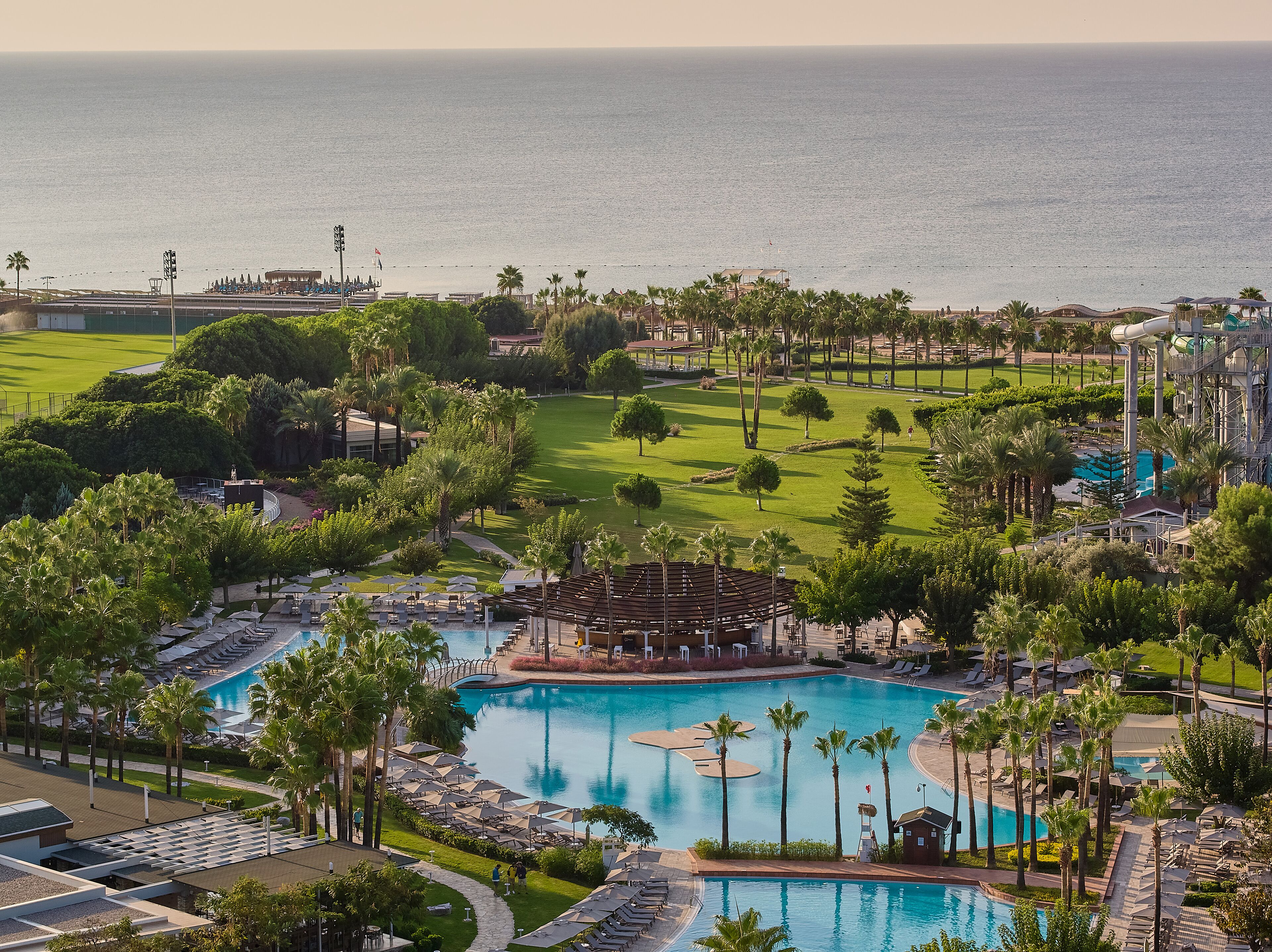 Ein Resort mit mehreren Schwimmbecken, einem Golfplatz und Blick auf den Ozean.