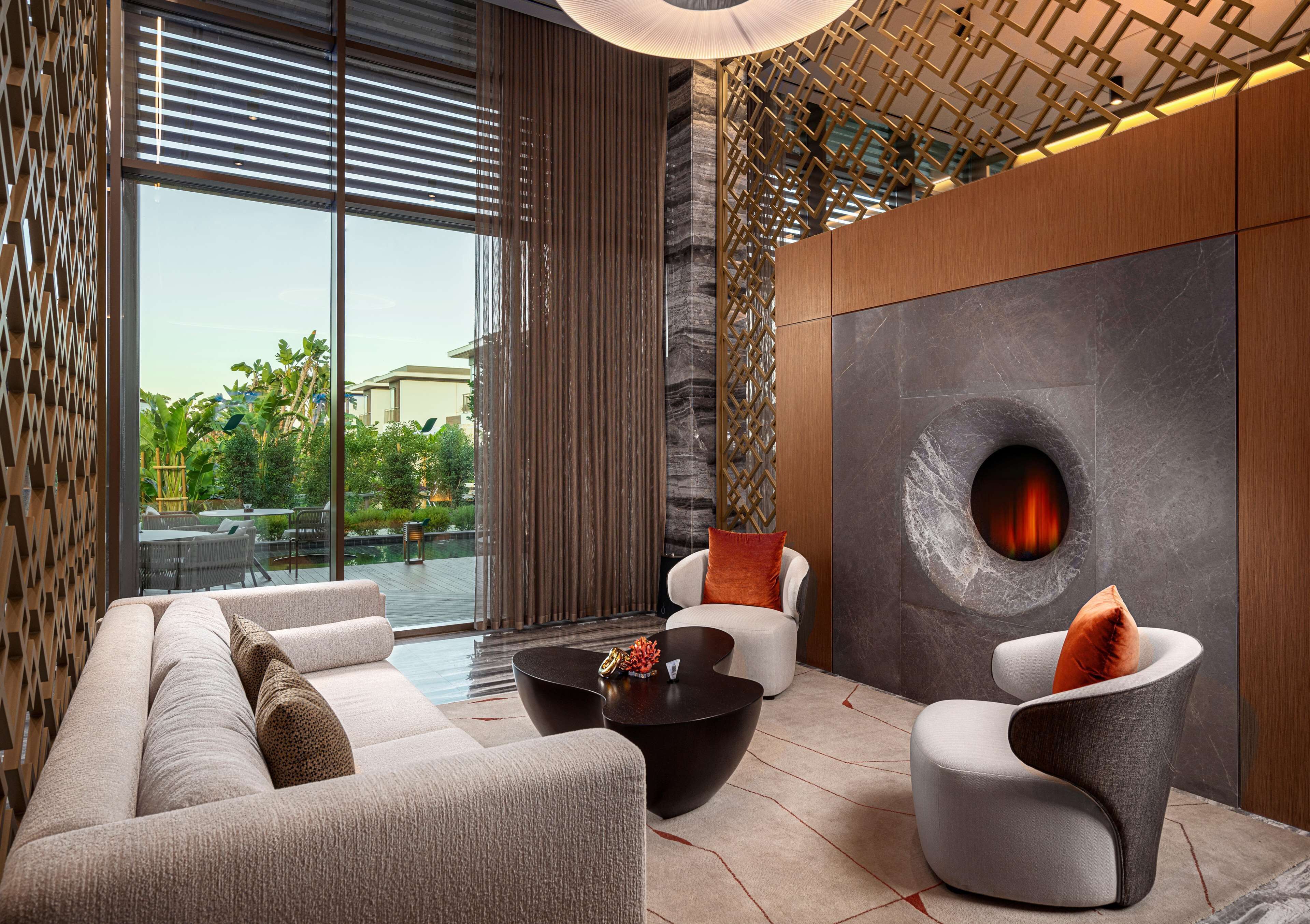A modern lounge area with a sofa, two armchairs, a coffee table, and a fireplace.
