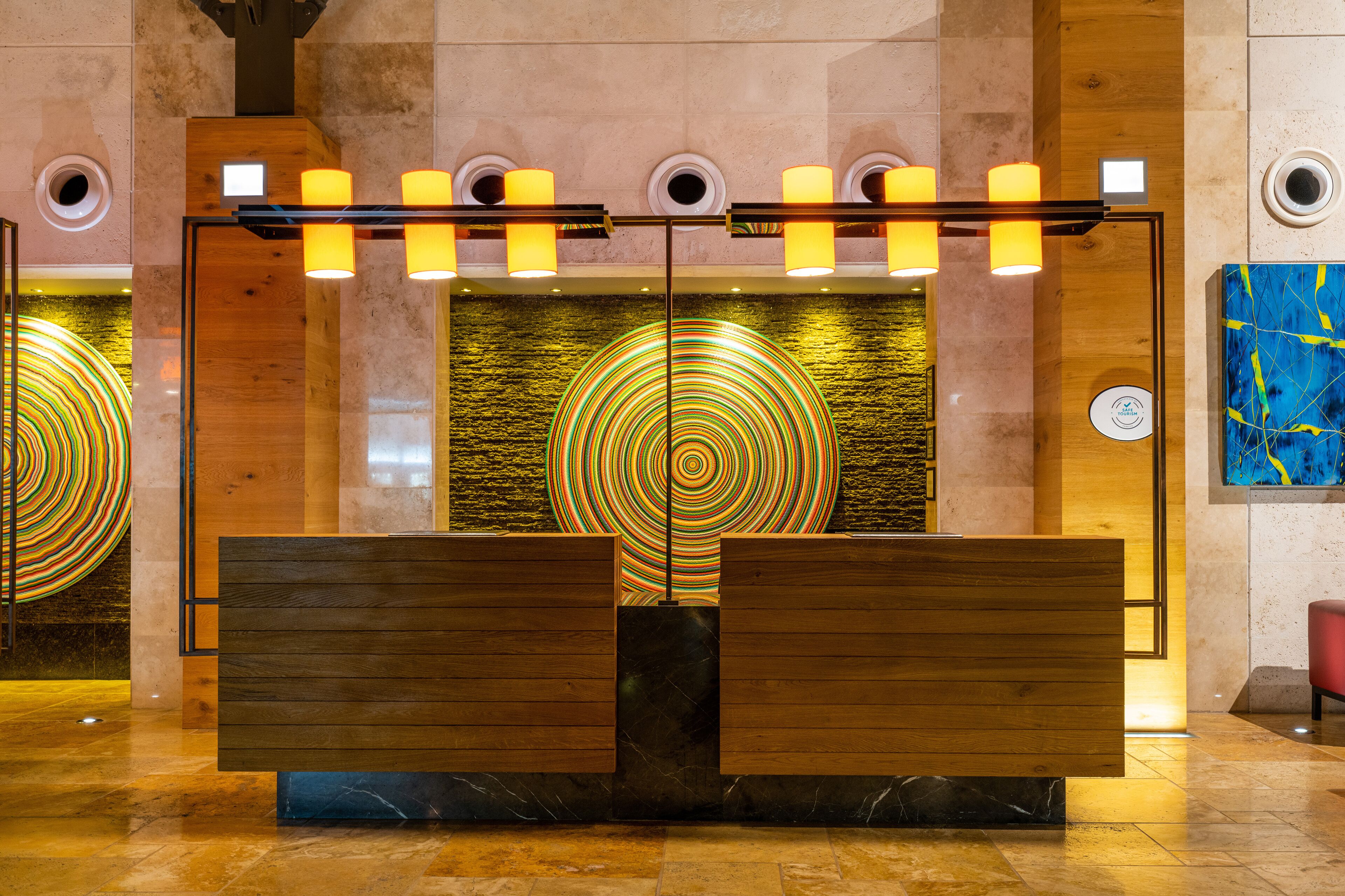 A reception area with a wooden bench, a circular light installation, and a modern wall design.