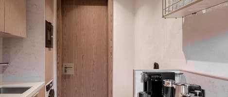 A modern kitchen with wooden cabinets, a marble countertop, and a coffee maker.