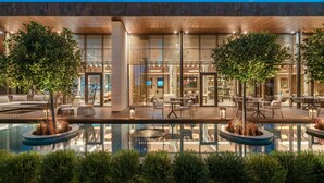 A modern hotel with a pool area, outdoor seating, and a well-lit entrance.