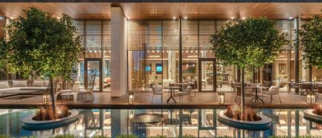 A modern hotel with a pool area, outdoor seating, and a well-lit entrance.
