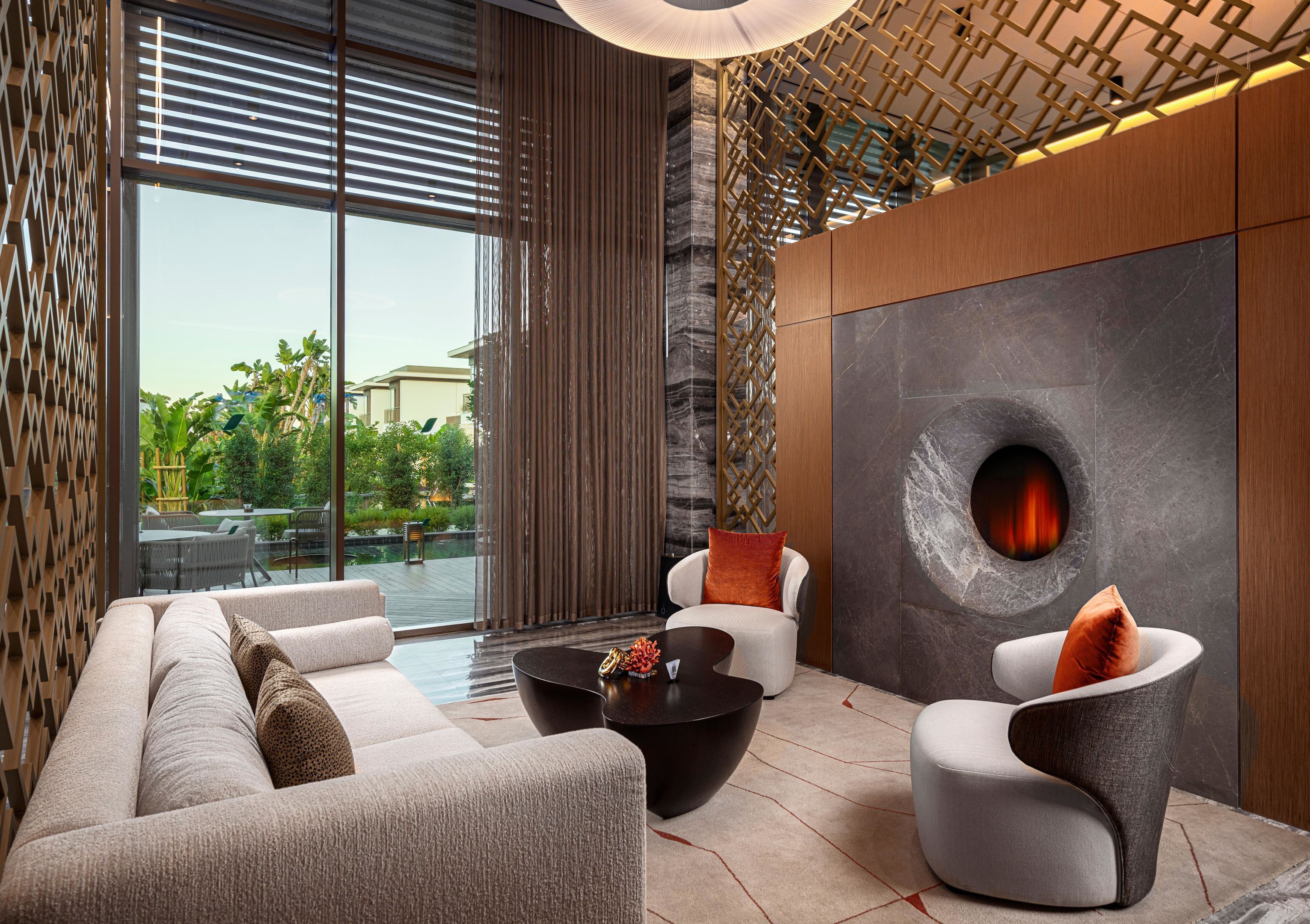 Eine moderne Lounge mit einer Couch, Sesseln, einem Couchtisch und einem Kamin.