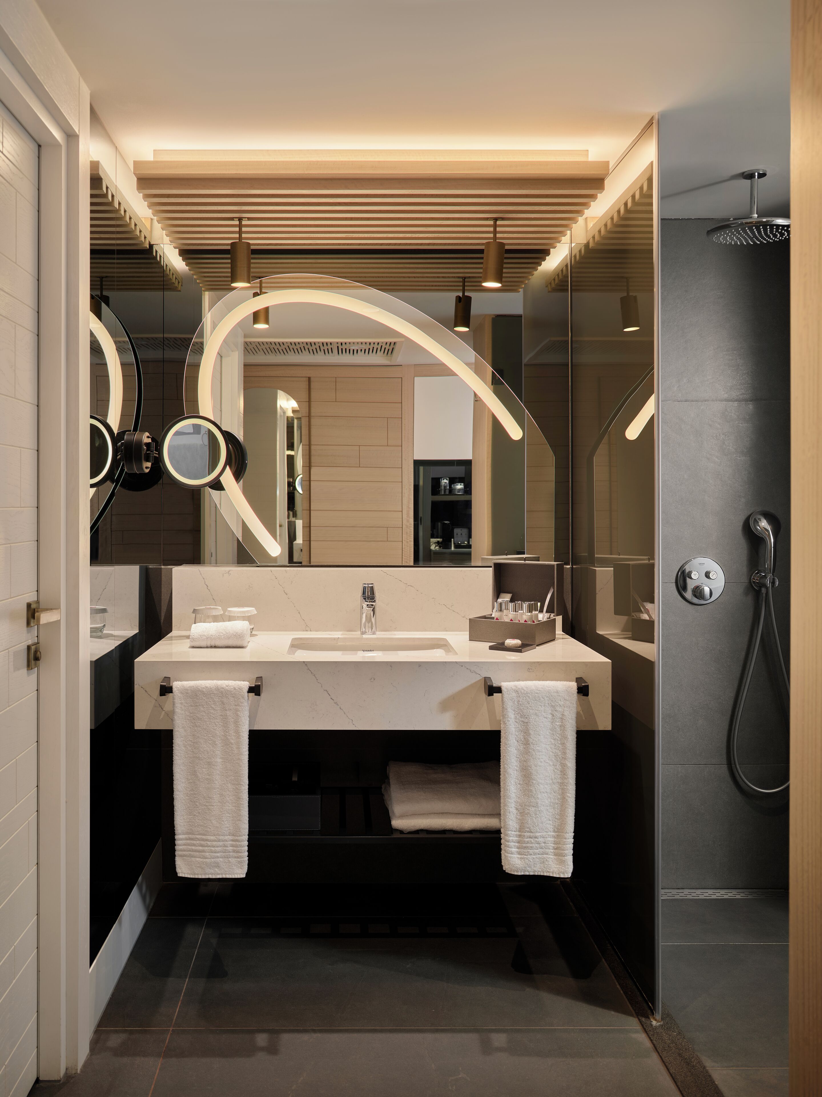 A modern bathroom with a double sink, a large mirror, and a shower.