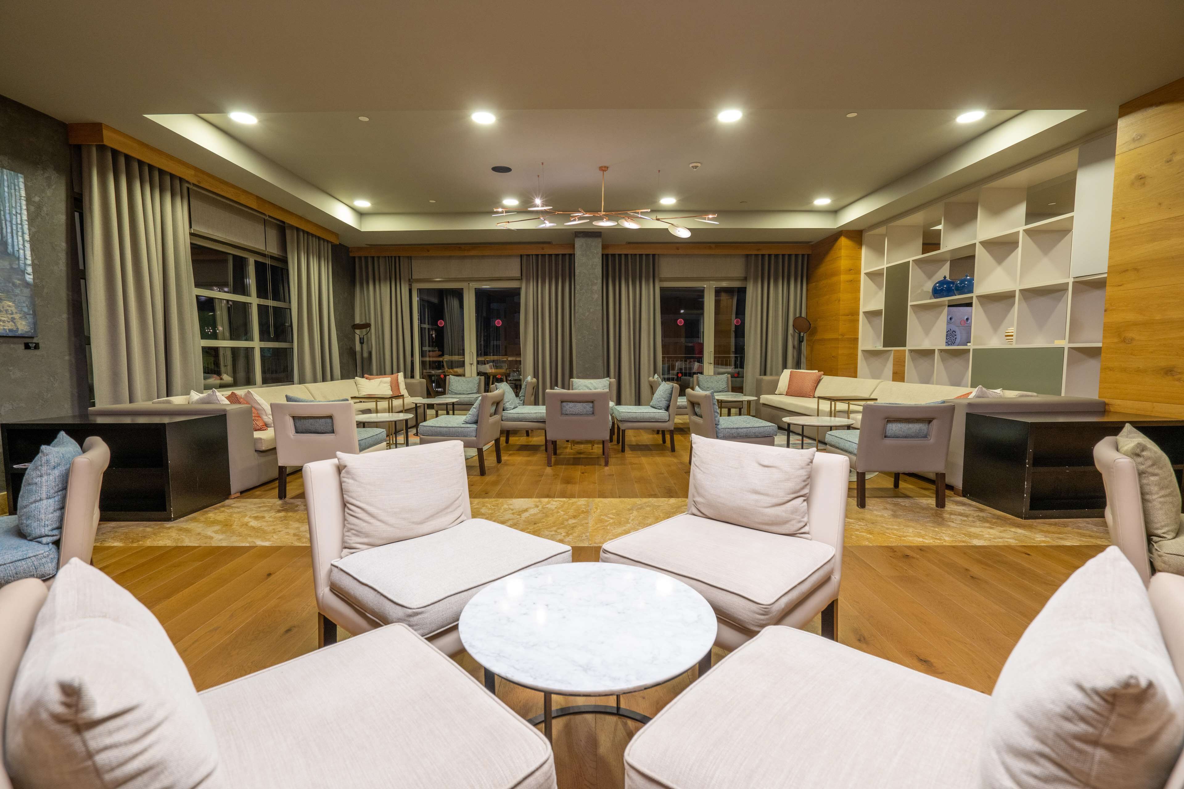 A spacious lounge area with multiple seating options, including sofas and armchairs, arranged around a central coffee table.