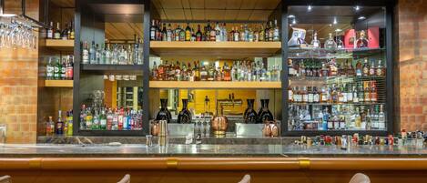 Un espace bar doté de plusieurs étagères remplies de bouteilles d’alcool, d’un comptoir et de tabourets de bar.