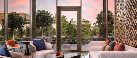 A modern outdoor seating area with contemporary furniture, a glass door leading to a deck, and a view of the surrounding landscape.