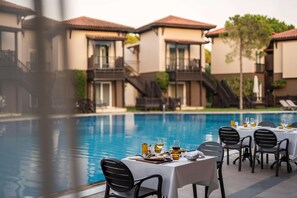A poolside dining area with tables set for two, overlooking a swimming pool. - Papillon Ayscha (Serik)