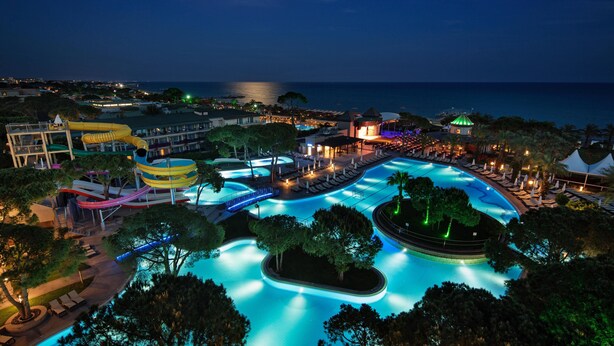 Ein Resort mit großem Schwimmbad, Wasserrutsche und Blick auf den Strand.