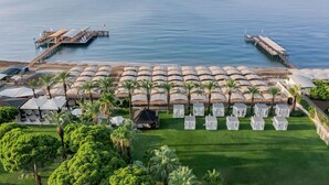 Eine Luftaufnahme eines Resorts mit Strandlage, inklusive Steg, Sonnenschirmen und einem gepflegten Rasen.