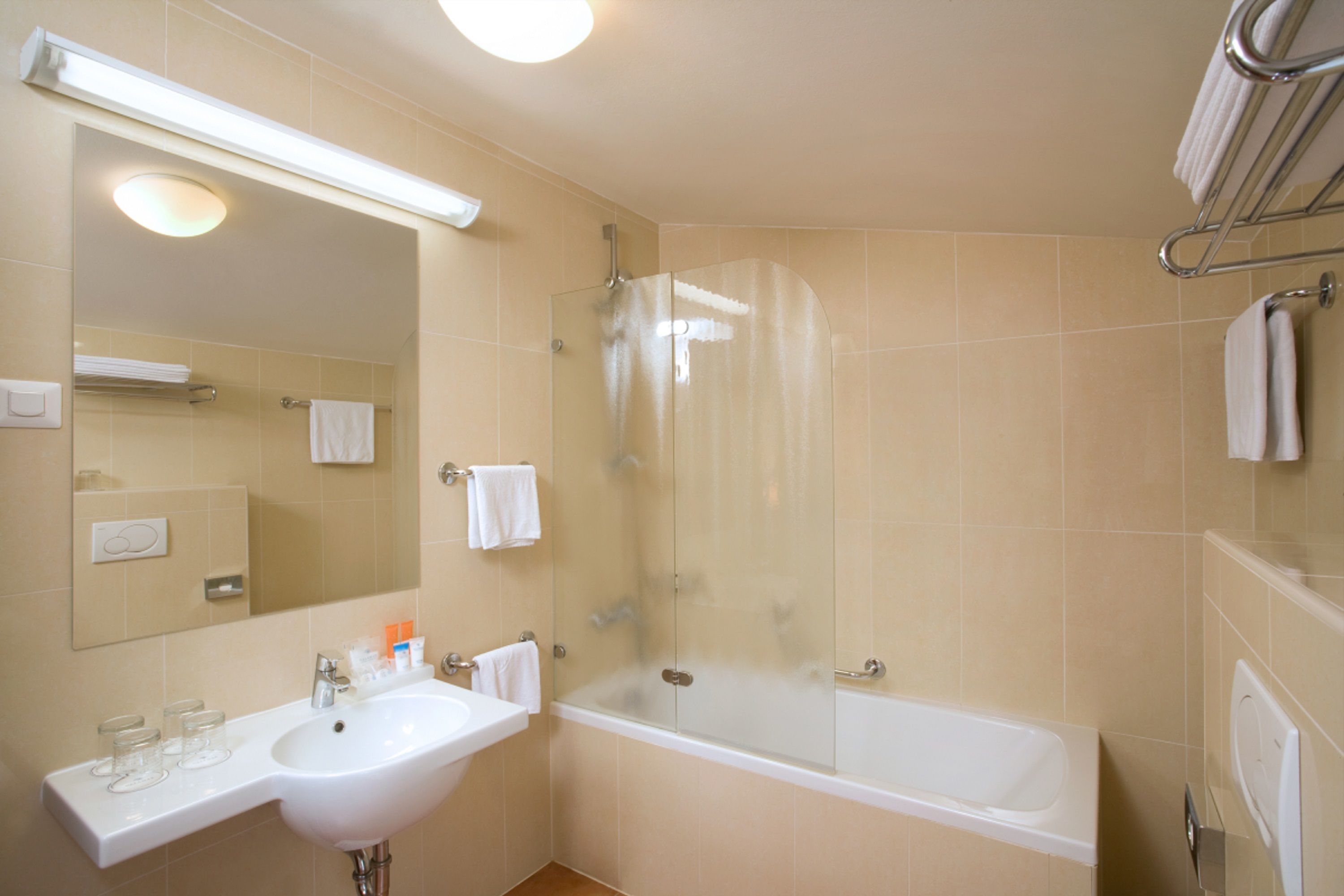 A bathroom with a sink, mirror, and a glass-enclosed shower.
