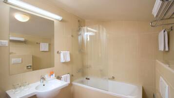 A bathroom with a sink, mirror, and a glass-enclosed shower.