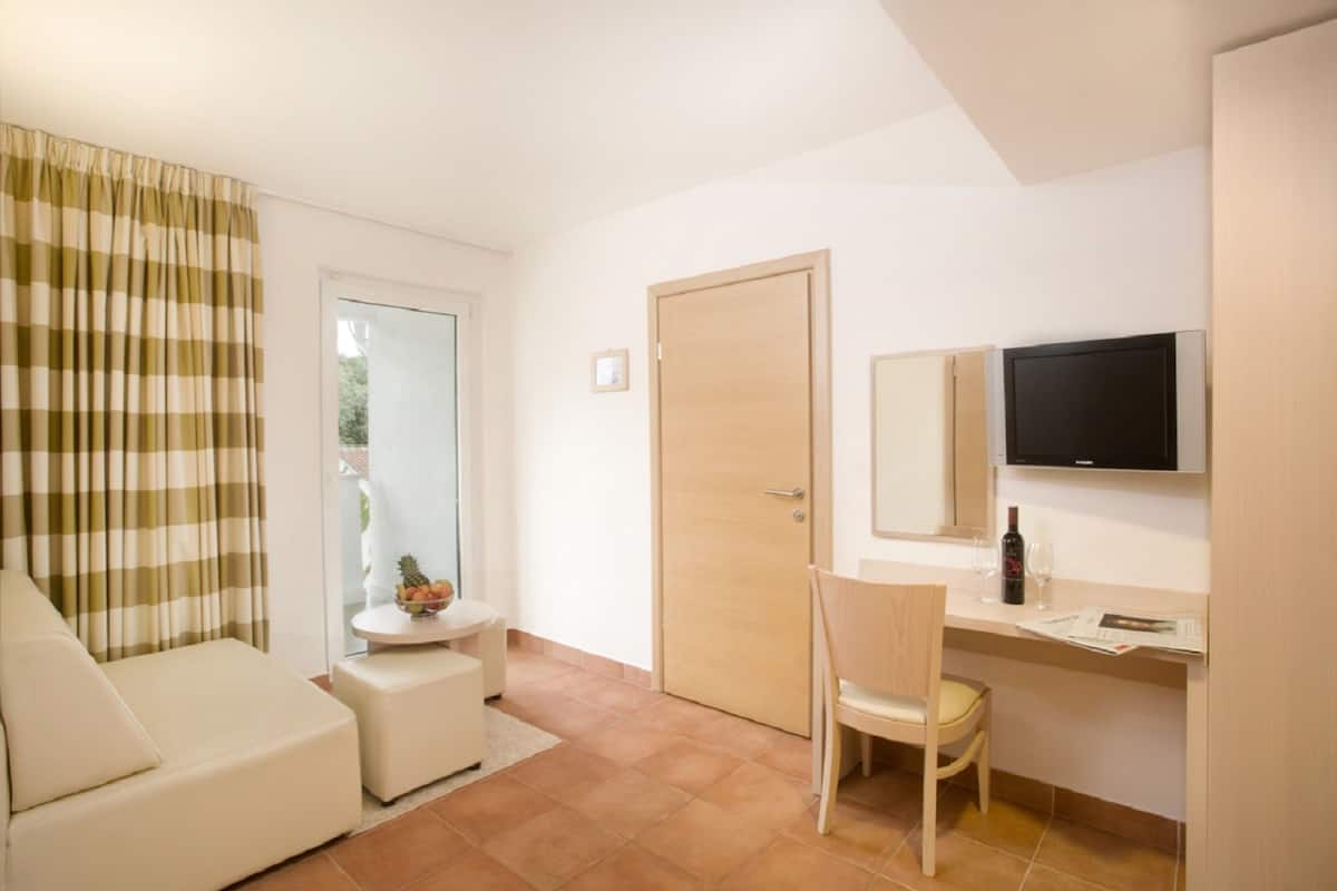 A modern room with a sofa, a small table with a fruit bowl, a wooden door, and a desk with a chair.