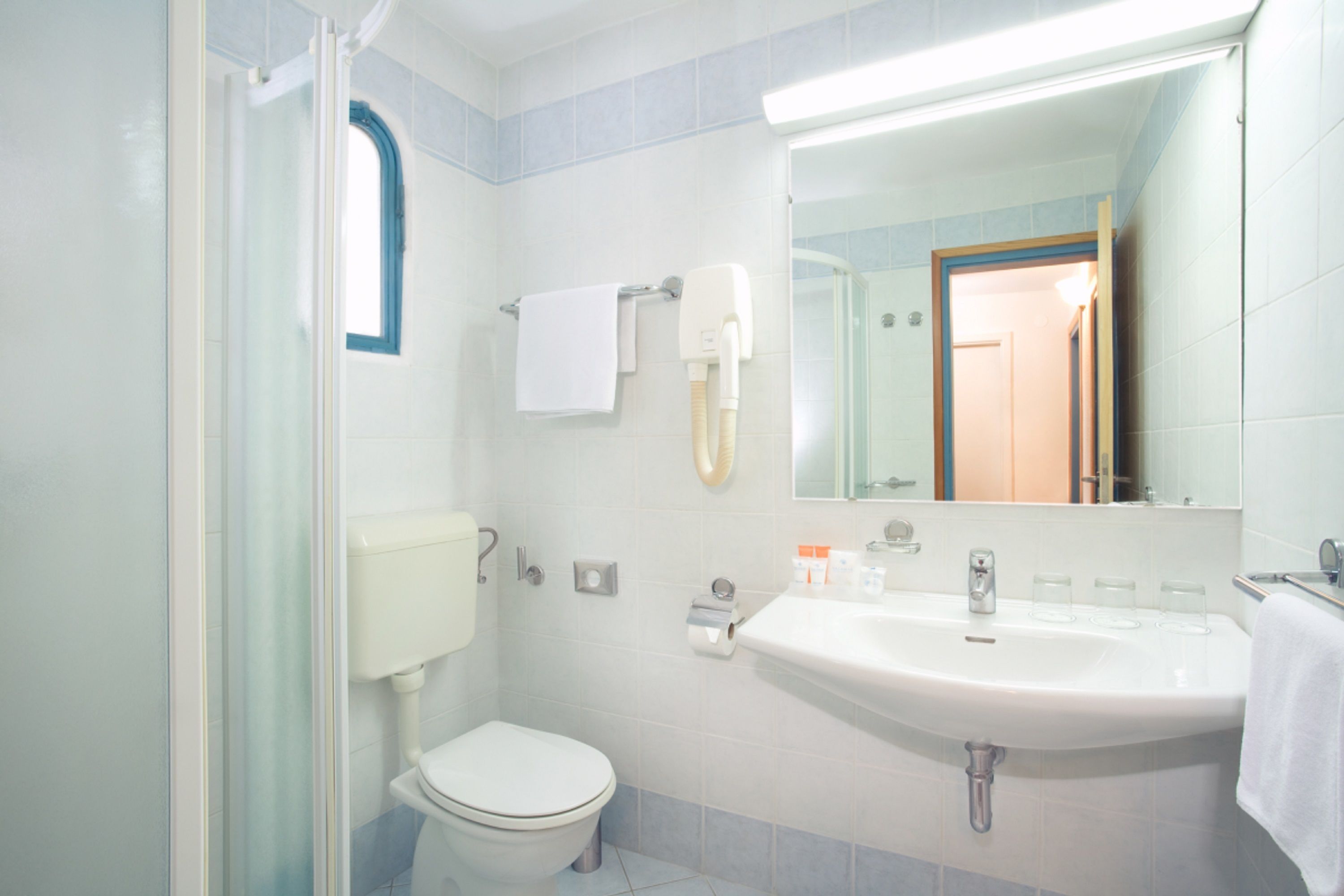 A bathroom with a toilet, sink, and a mirror.