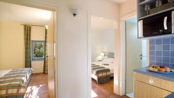 A hotel room with a bed, a small kitchenette, and a bathroom.