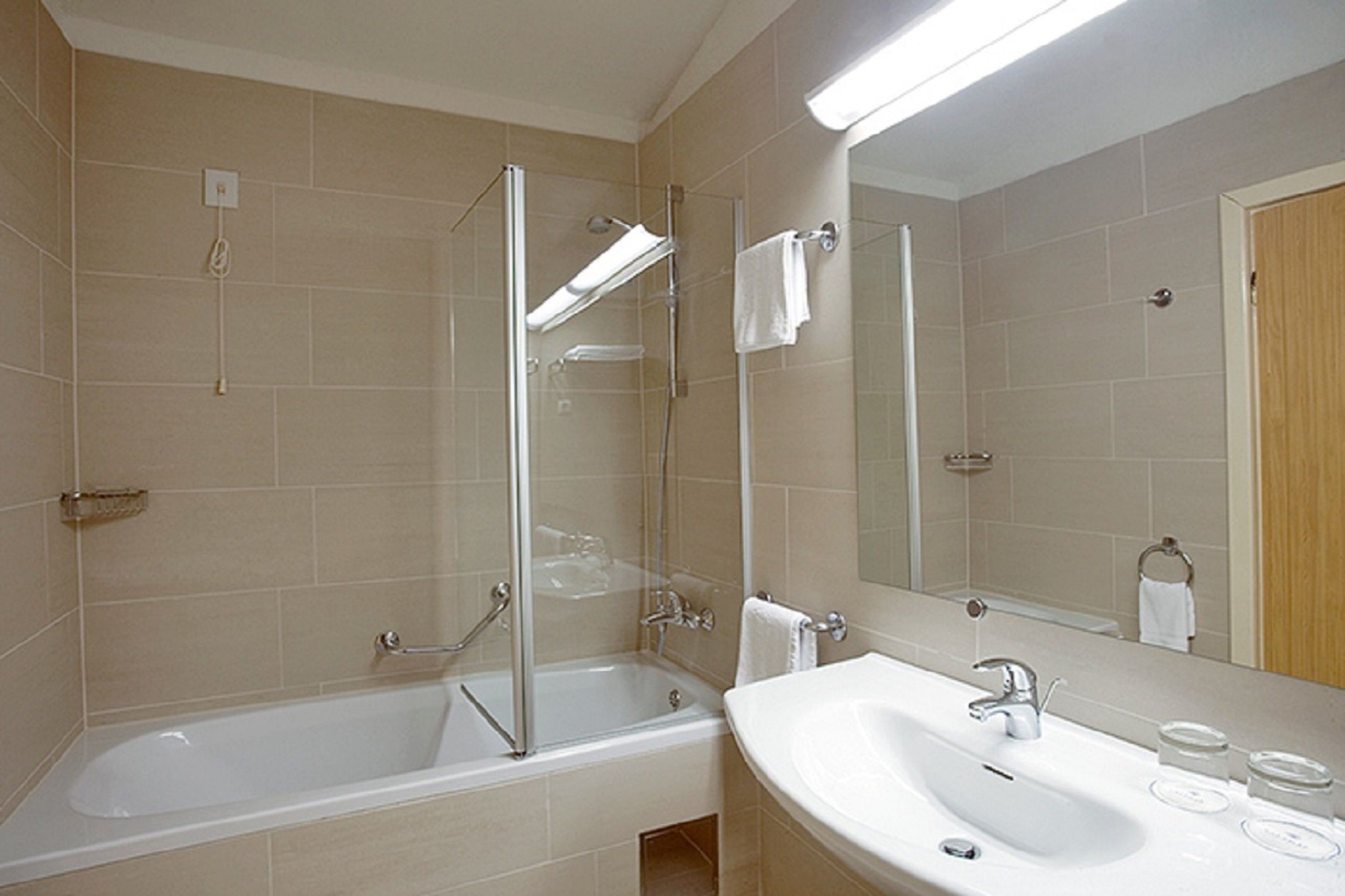 A modern bathroom with a bathtub, shower, and sink.