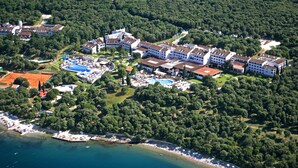 Vista aérea de un complejo turístico con varias edificaciones, una piscina y una zona de playa.