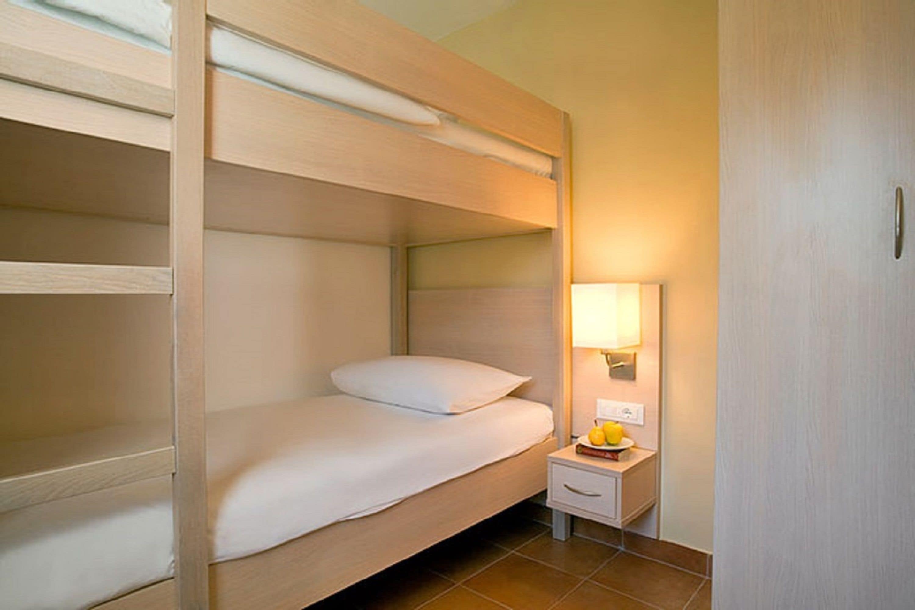A bunk bed room with a bedside table and a lamp.