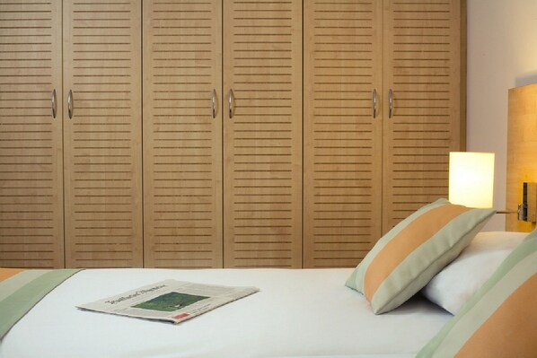 Un dormitorio con una cama, un periódico y armarios de madera.