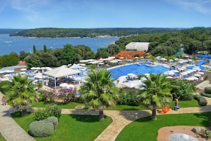 Un resort con una amplia piscina, palmeras y vista al mar.