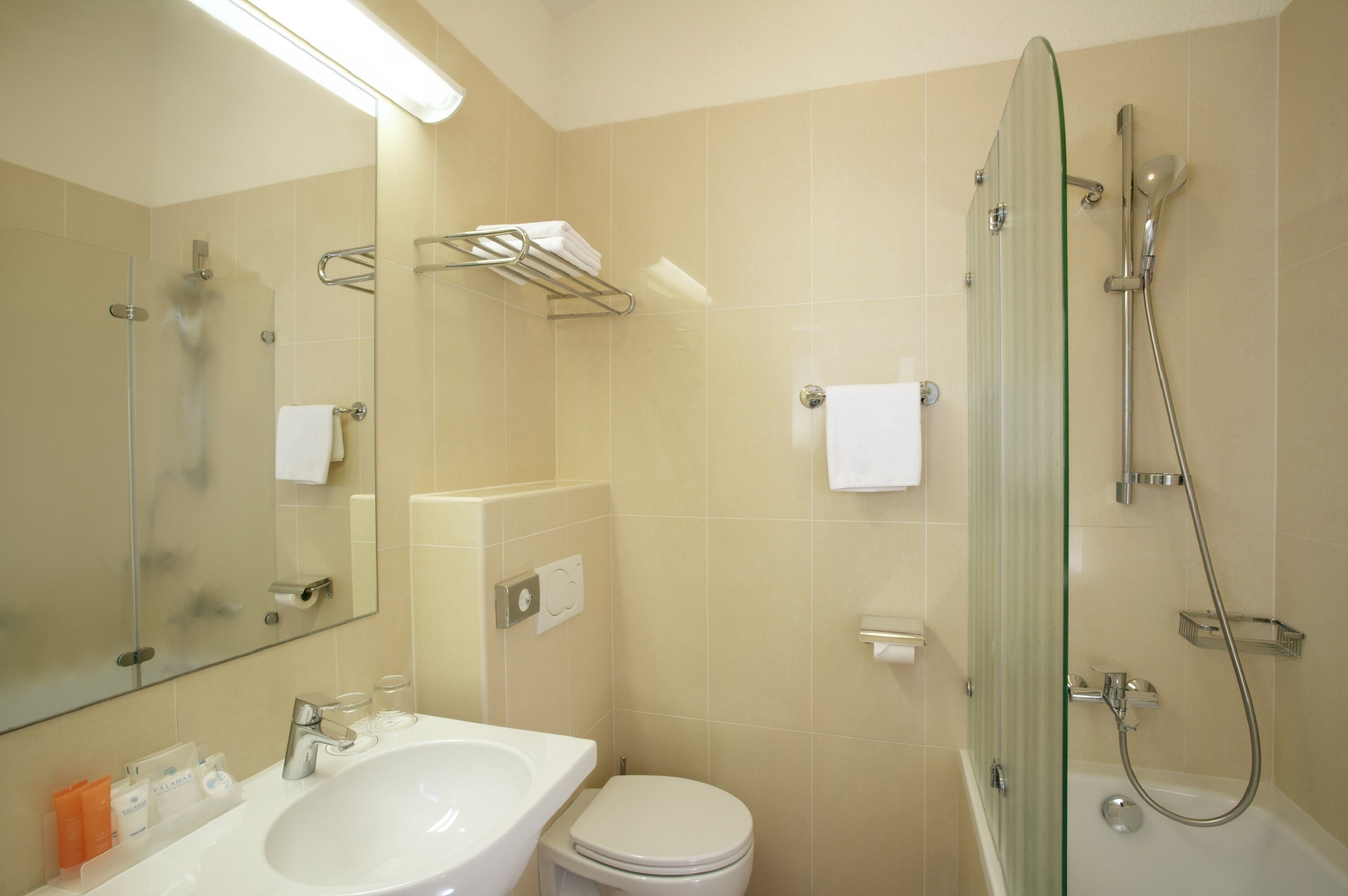 A bathroom with a glass-enclosed shower, a white sink, and a toilet.