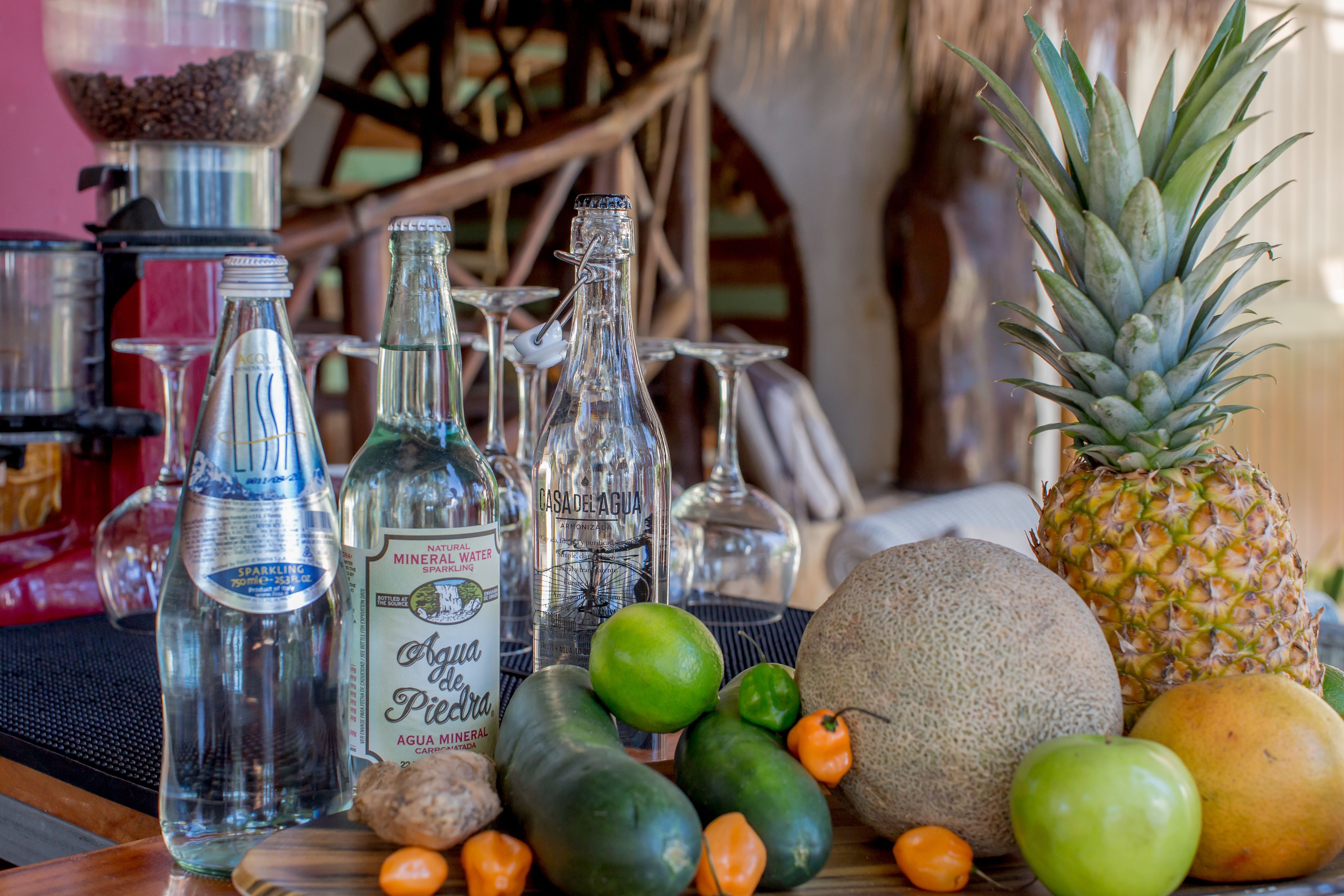 A table with various bottles, glasses, and fruits.