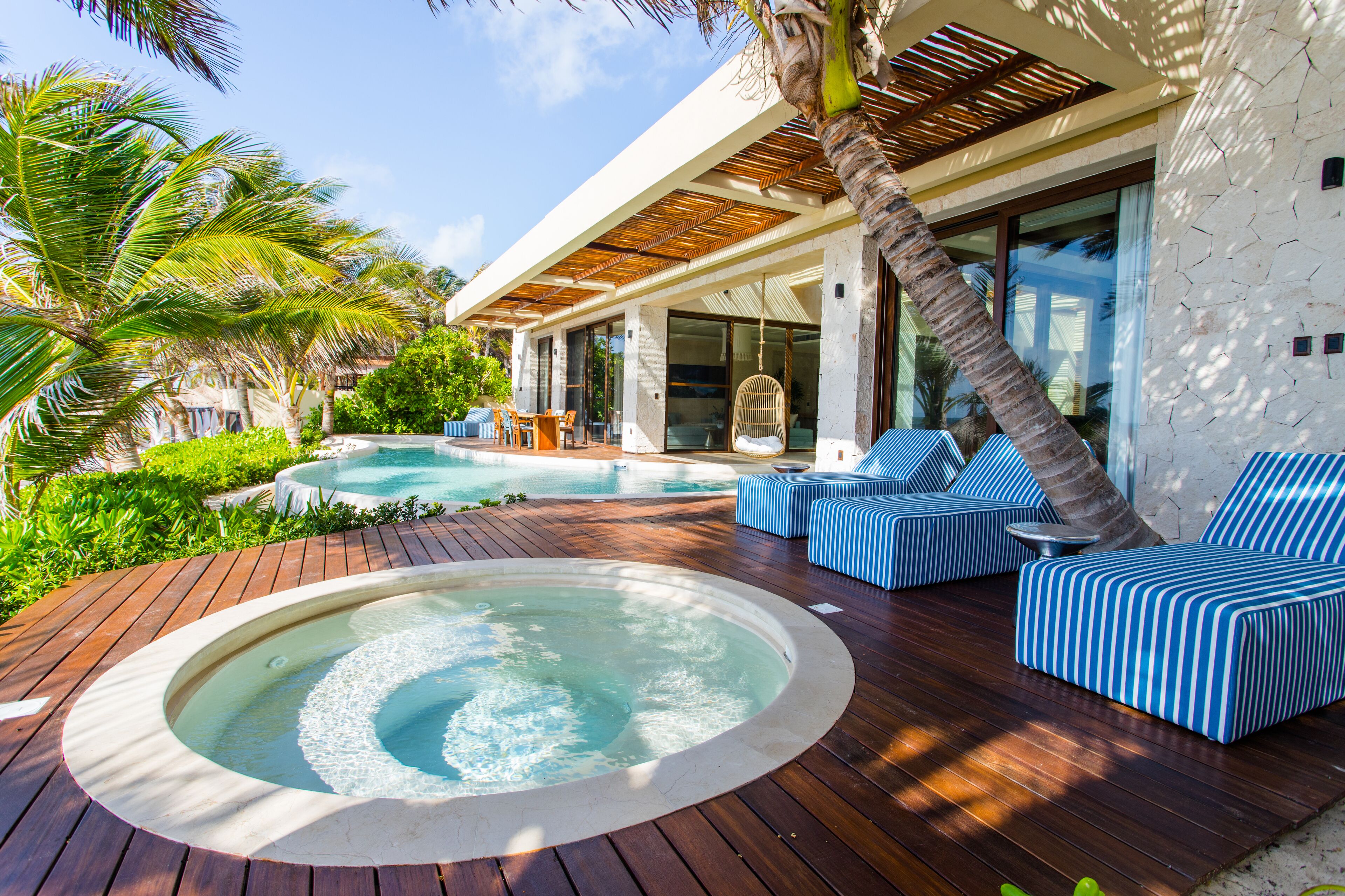 A modern outdoor pool area with a hot tub, lounge chairs, and a wooden deck.