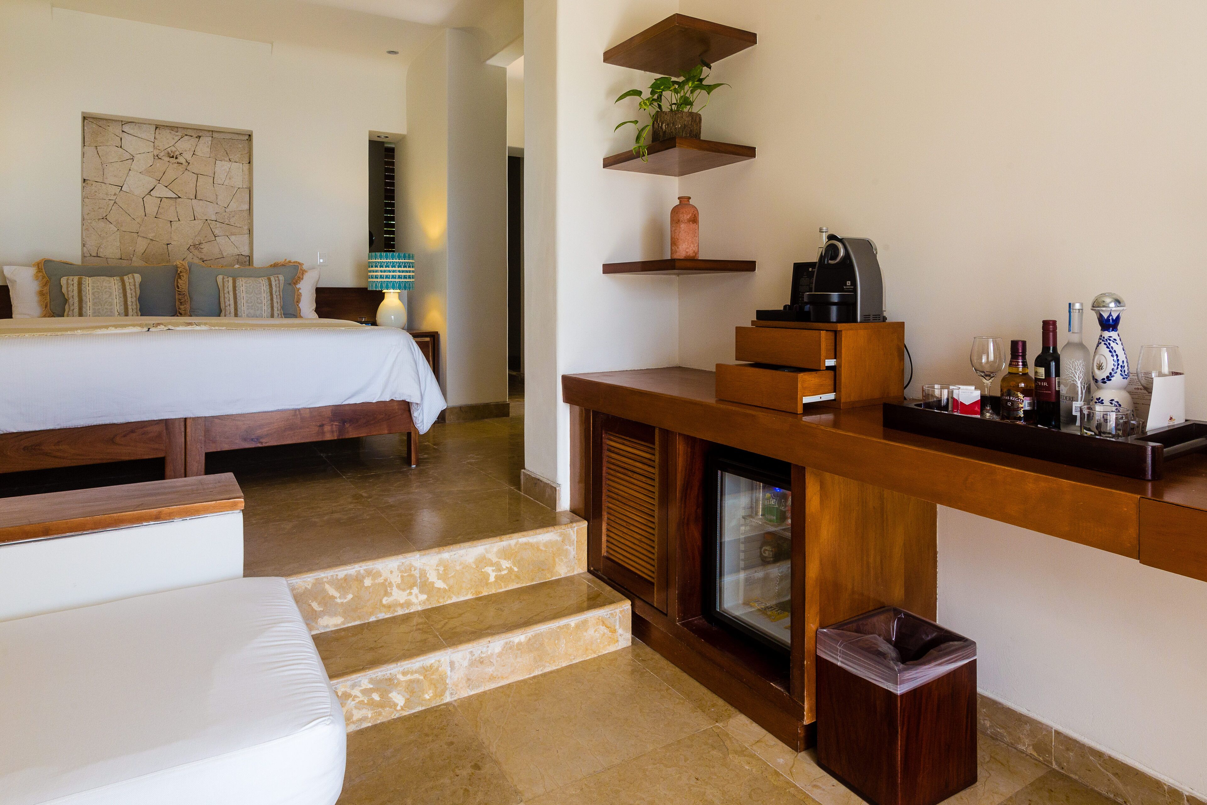 A hotel room with a bed, a seating area, a kitchen counter with various items, and a staircase.