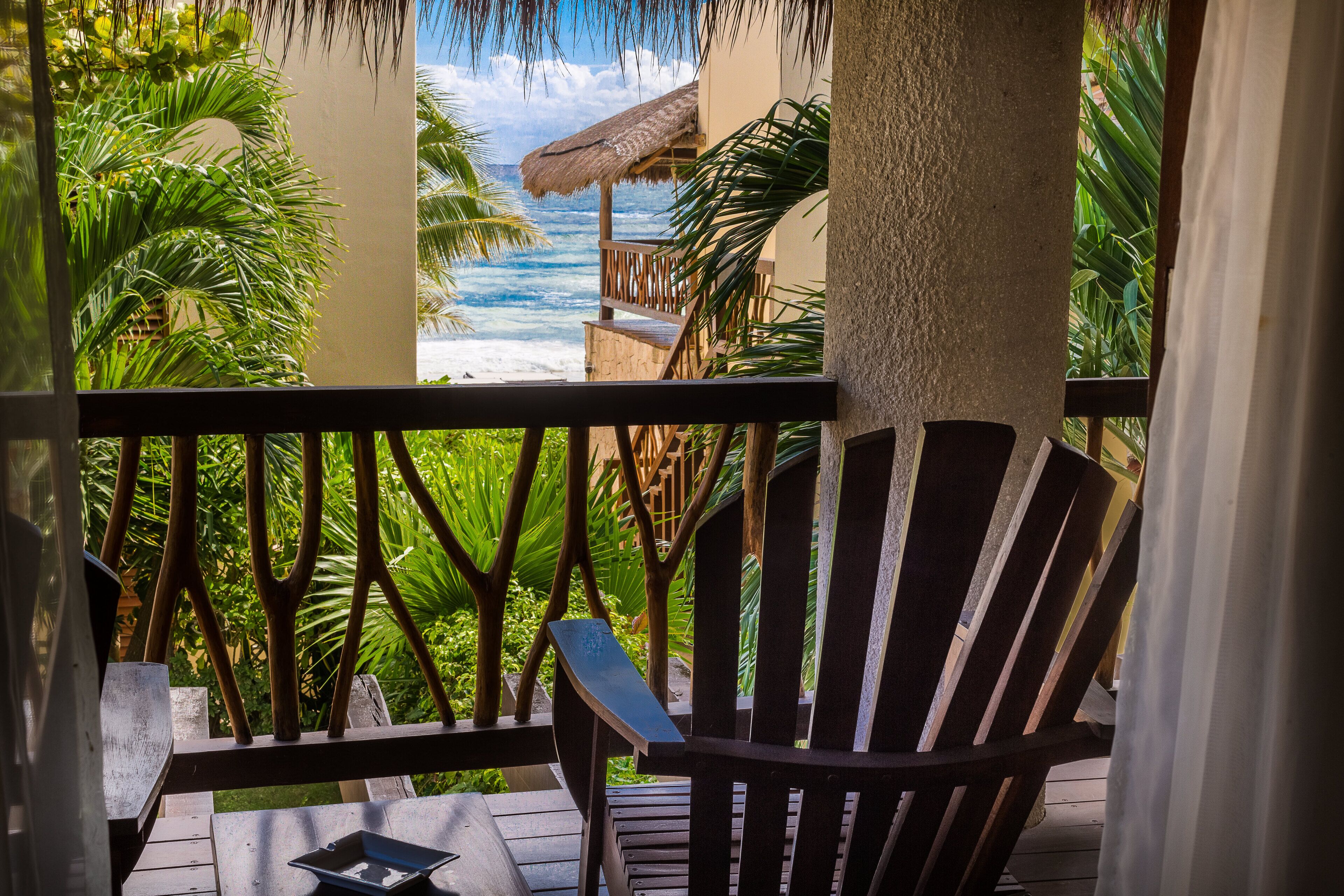 A wooden chair with a tray on a balcony overlooking a beach.