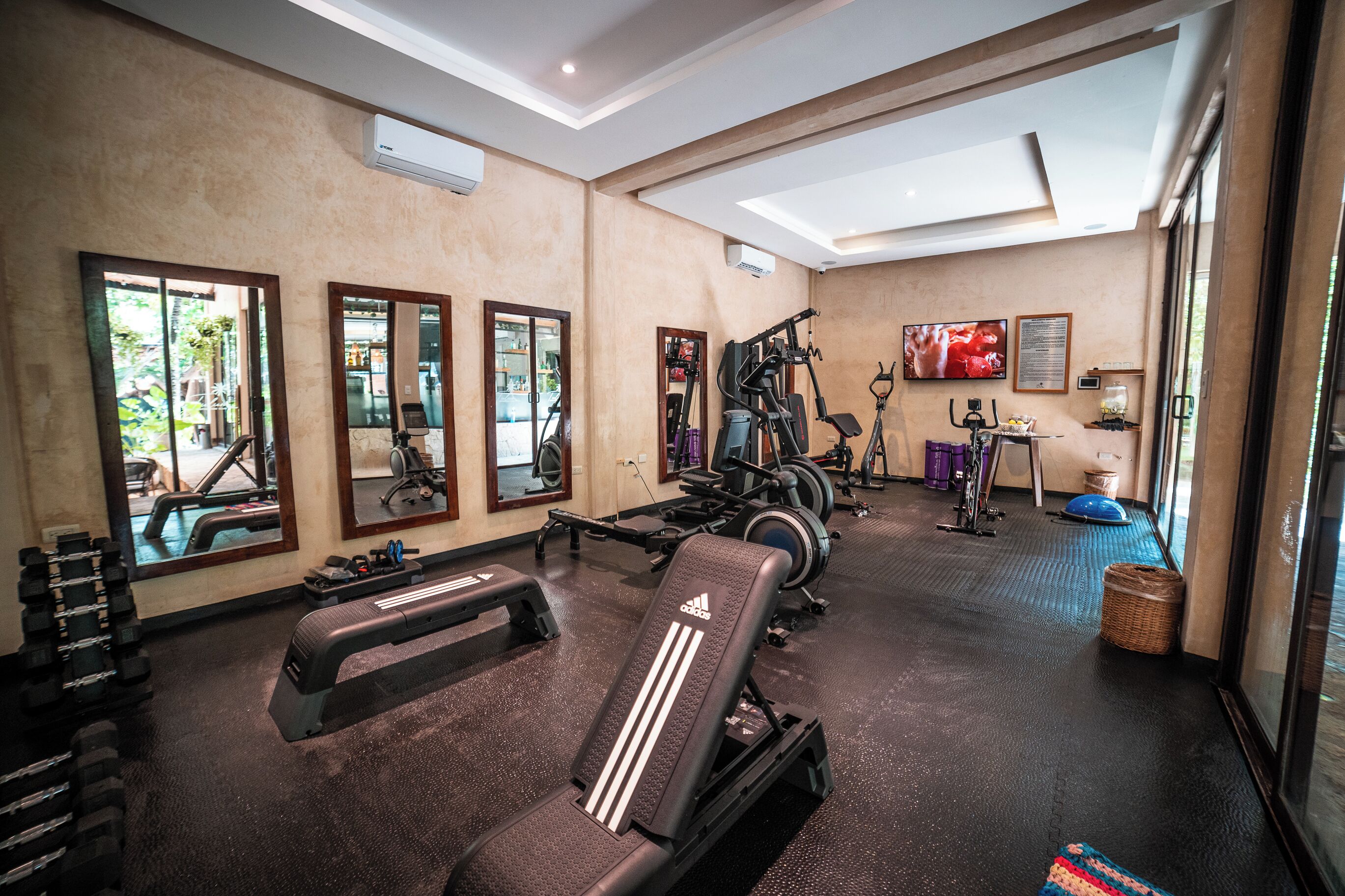Une salle de sport équipée de matériel d’exercice, de miroirs et d’un téléviseur.