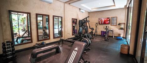 Une salle de sport équipée de matériel d’exercice, de miroirs et d’un téléviseur.