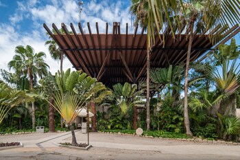 A spacious room with a large dining table, wicker chairs, and hanging wicker lamps. There is a sofa and a large mirror on the wall. at Ana y Jose Tulum Hotel & Spa