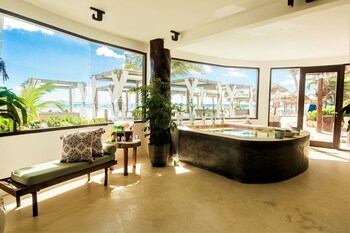 A beachfront property with a modern design, featuring a well-lit entrance, palm trees, and a sandy beach. at Ana y Jose Tulum Hotel & Spa