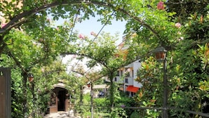 A garden pathway with a pergola covered in climbing plants and flowers, leading to a building entrance. - Balletti Park Hotel (Viterbo)