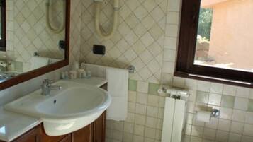 Ein Badezimmer mit Waschbecken, Spiegel, Toilette, Bidet und einem Fenster.